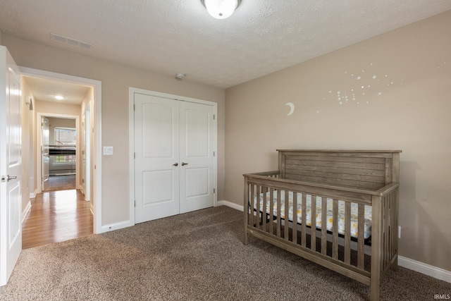 carpeted bedroom with visible vents, a closet, and baseboards