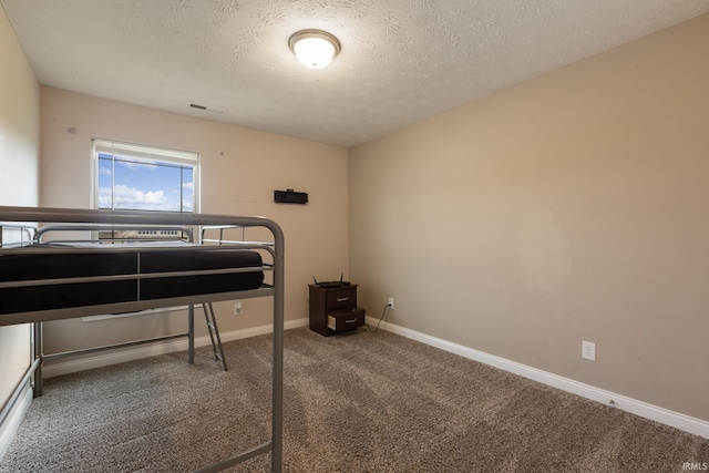 carpeted bedroom featuring a textured ceiling, baseboards, and visible vents