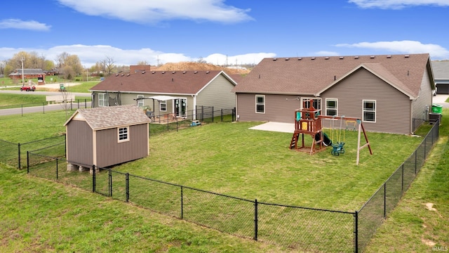 back of property featuring an outbuilding, a shed, a yard, a fenced backyard, and a playground