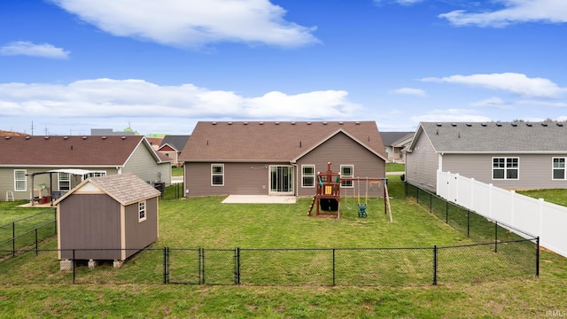 back of property featuring a storage shed, a fenced backyard, an outdoor structure, a lawn, and a playground