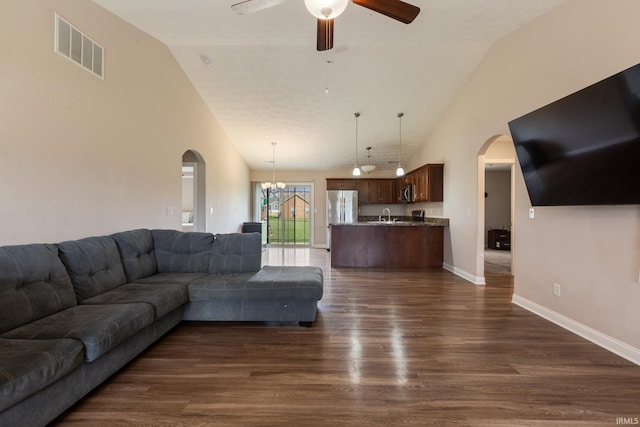 living room with dark wood-style flooring, visible vents, arched walkways, and ceiling fan with notable chandelier