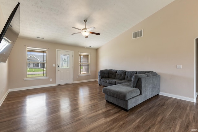 living area with visible vents, a ceiling fan, and dark wood finished floors
