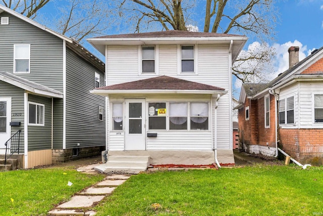 traditional style home with a front yard, roof with shingles, and entry steps