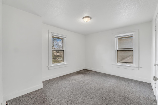 carpeted empty room featuring a textured ceiling and baseboards