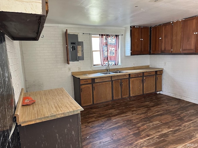 kitchen with electric panel, dark wood-style flooring, light countertops, a sink, and brick wall