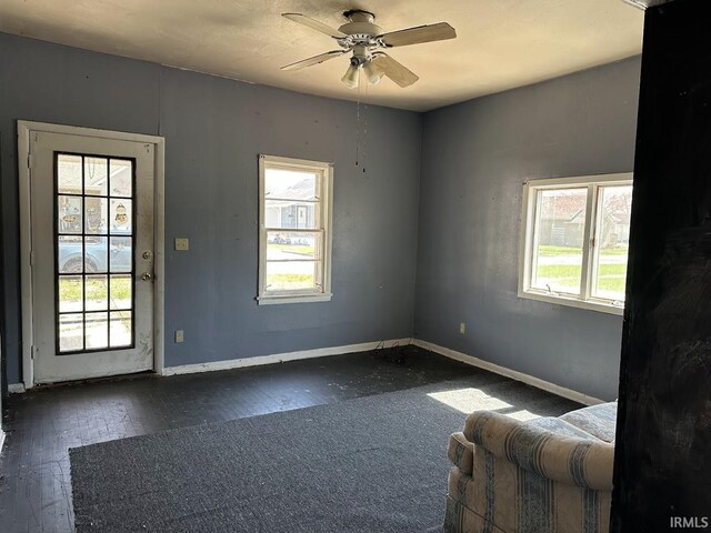 interior space with baseboards, hardwood / wood-style floors, and ceiling fan