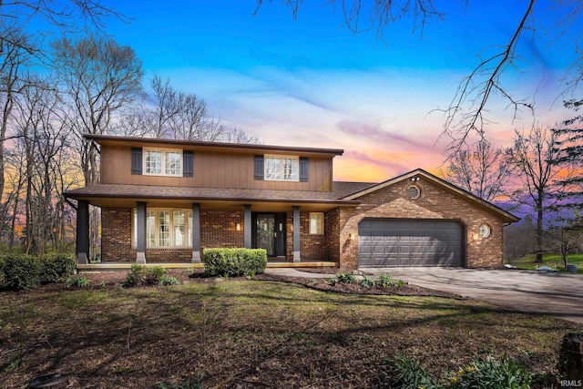 traditional home with brick siding, a porch, an attached garage, and concrete driveway