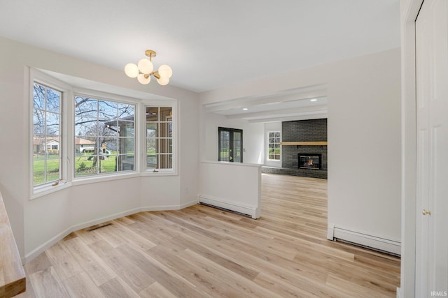 unfurnished dining area featuring a baseboard radiator, an inviting chandelier, and a healthy amount of sunlight