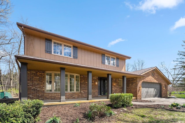 traditional home featuring a porch, an attached garage, concrete driveway, and brick siding