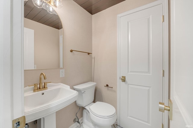 bathroom featuring toilet, wooden ceiling, and a sink