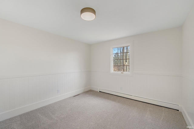 carpeted spare room with wainscoting and a baseboard heating unit