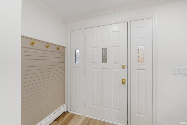 foyer entrance featuring ornamental molding, a baseboard radiator, and light wood-type flooring