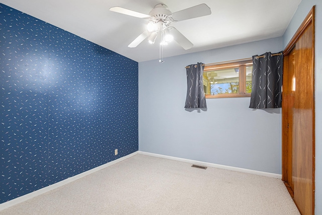 carpeted empty room with baseboards, a ceiling fan, wallpapered walls, and visible vents