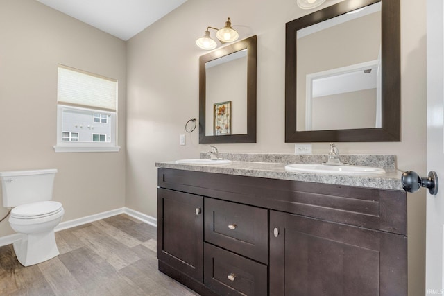 full bathroom featuring a sink, toilet, wood finished floors, and baseboards