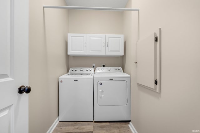 laundry area with cabinet space, washing machine and clothes dryer, baseboards, and light wood-style flooring