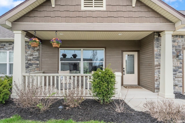 view of exterior entry with stone siding and covered porch