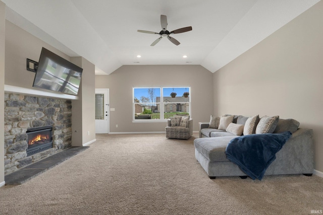 carpeted living area with a stone fireplace, ceiling fan, vaulted ceiling, and baseboards