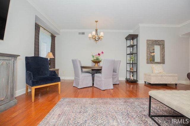 dining area with an inviting chandelier, ornamental molding, and wood finished floors