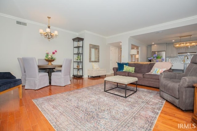 living area with light wood-type flooring, an inviting chandelier, and visible vents