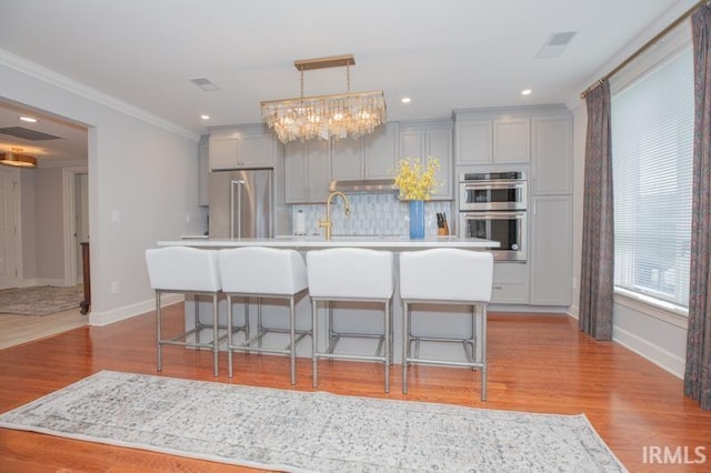 kitchen with gray cabinets, light countertops, stainless steel appliances, baseboards, and backsplash