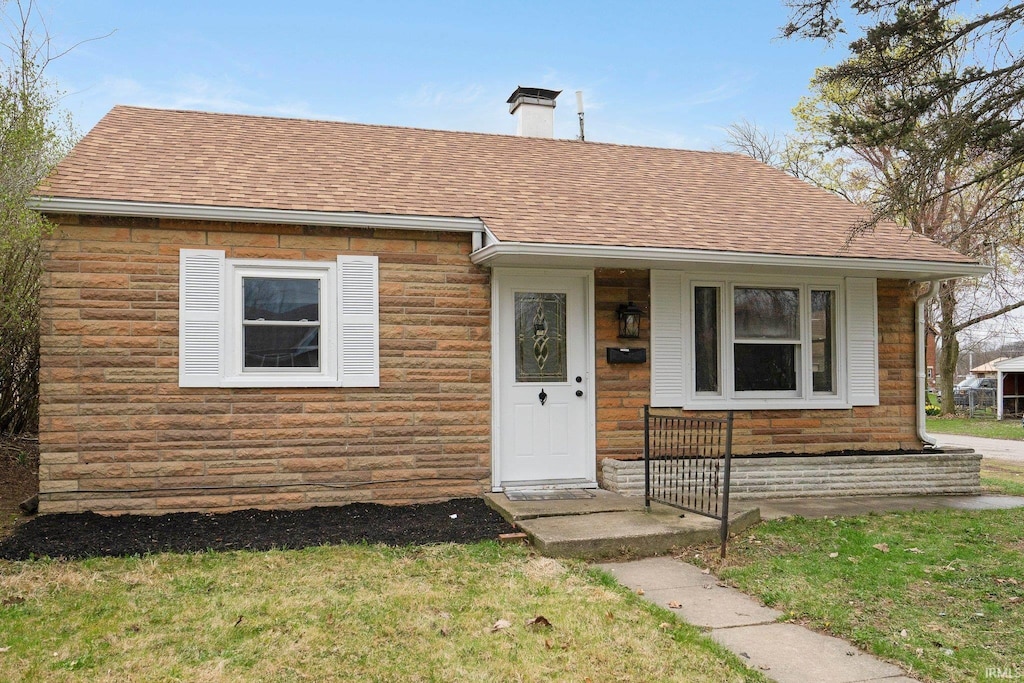 bungalow-style home with stone siding, a chimney, and a shingled roof