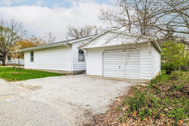 exterior space featuring a front yard, a garage, and gravel driveway