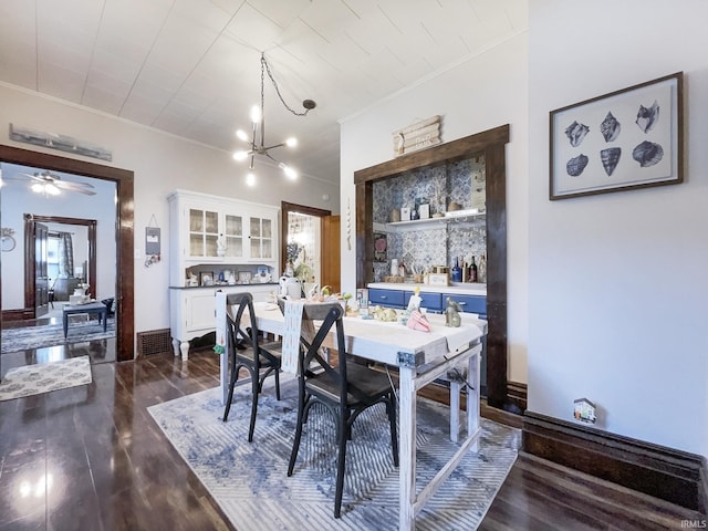 dining space featuring an inviting chandelier, dark wood-type flooring, visible vents, and crown molding