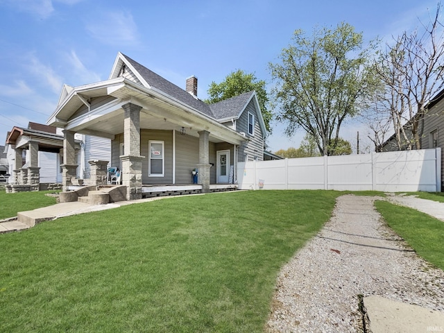view of side of home featuring a yard, fence, covered porch, and a chimney