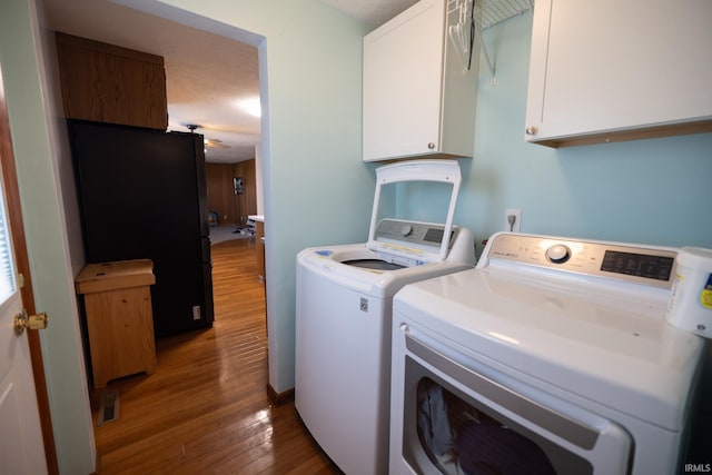 laundry area with washing machine and dryer, visible vents, wood finished floors, and cabinet space