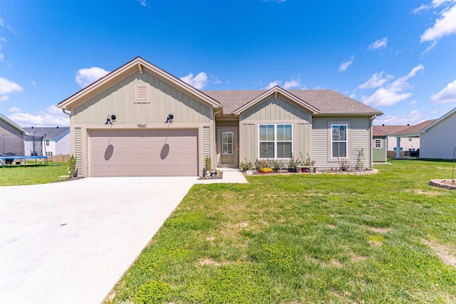 ranch-style house featuring a trampoline, driveway, board and batten siding, an attached garage, and a front yard