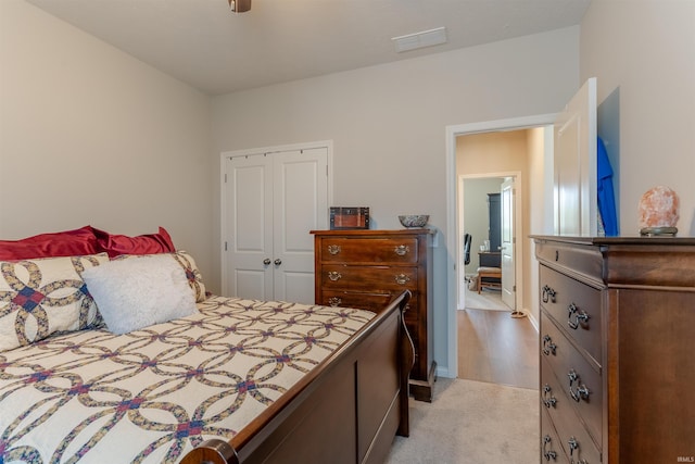 bedroom with visible vents, a closet, and light colored carpet