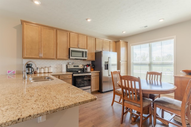 kitchen featuring backsplash, a sink, light brown cabinetry, and appliances with stainless steel finishes