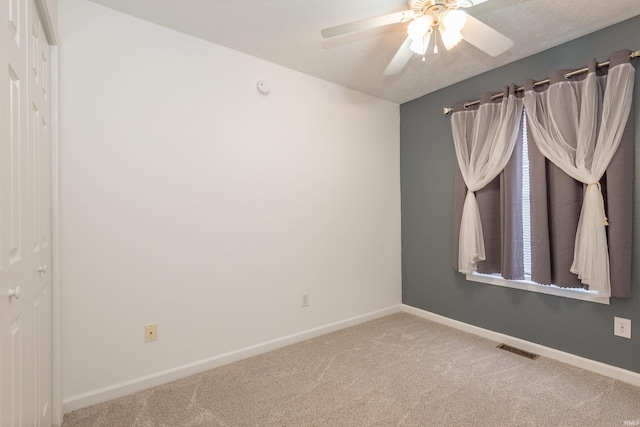 carpeted empty room with ceiling fan, baseboards, and visible vents