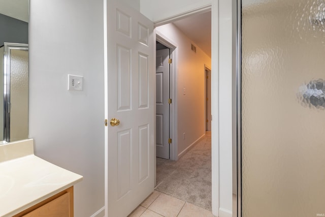 hallway with visible vents, baseboards, light carpet, and light tile patterned floors