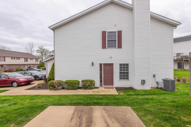 view of front of home featuring central AC unit, a front yard, and a chimney