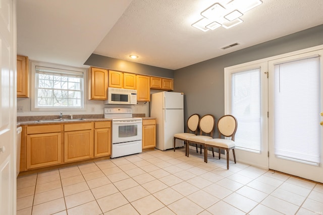 kitchen with light tile patterned floors, white appliances, a textured ceiling, visible vents, and a sink