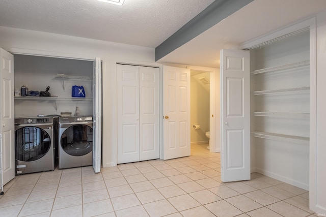 laundry room featuring baseboards, a textured ceiling, light tile patterned flooring, independent washer and dryer, and laundry area