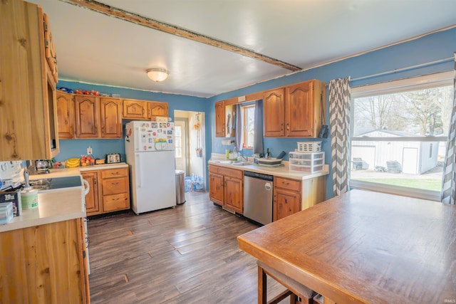 kitchen featuring light countertops, stainless steel dishwasher, freestanding refrigerator, and a healthy amount of sunlight