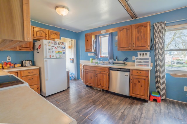 kitchen with dishwasher, light countertops, freestanding refrigerator, dark wood-style floors, and brown cabinetry