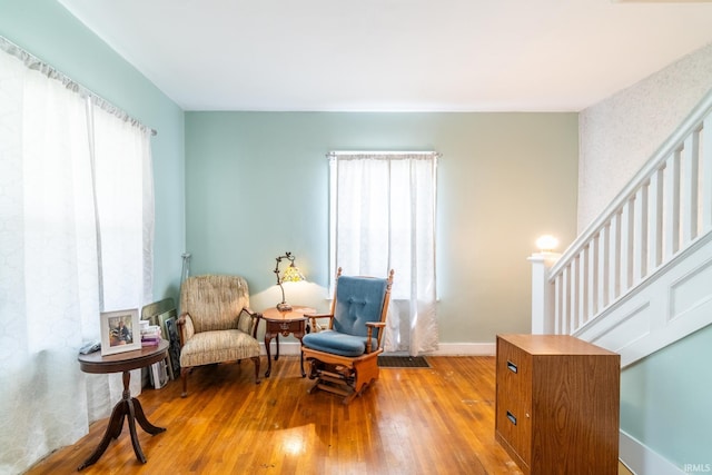 sitting room featuring hardwood / wood-style flooring, baseboards, and stairs
