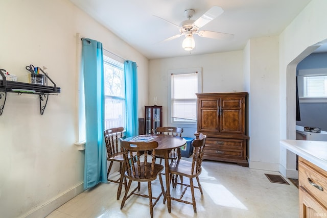dining space with arched walkways, baseboards, and light floors