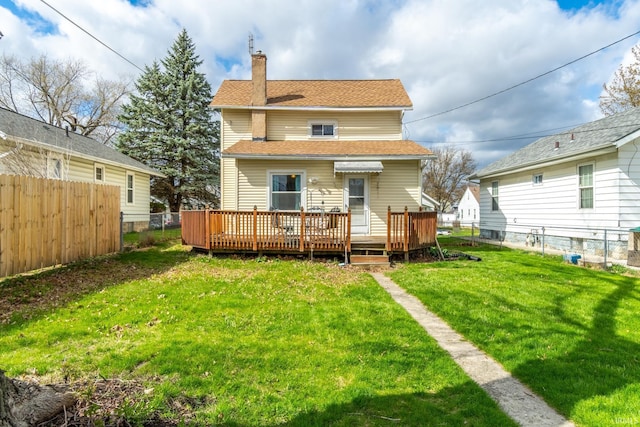 back of property with a fenced backyard, a wooden deck, a chimney, and a yard