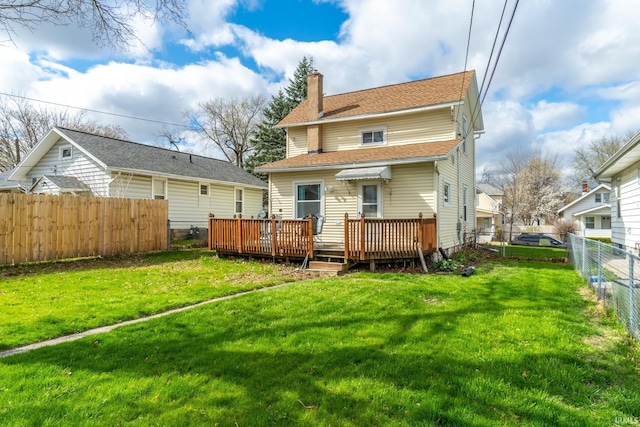 back of house featuring a wooden deck, a yard, a chimney, and a fenced backyard
