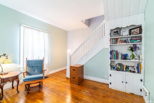 sitting room featuring wood-type flooring, stairway, and baseboards
