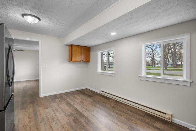 interior space with dark wood-type flooring, a baseboard radiator, baseboards, and a textured ceiling
