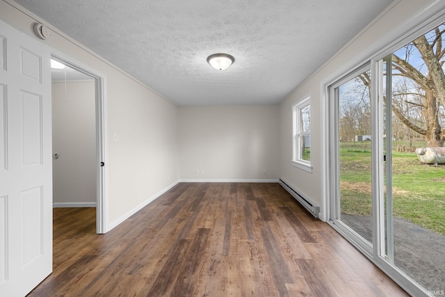 spare room featuring a textured ceiling, a baseboard heating unit, baseboards, and dark wood-style floors