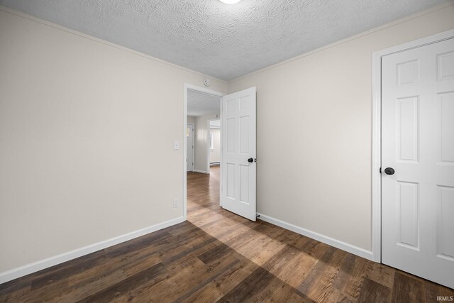 unfurnished bedroom featuring a textured ceiling, dark wood-style flooring, and baseboards