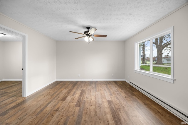 unfurnished room with a textured ceiling, a ceiling fan, wood finished floors, a baseboard heating unit, and baseboards