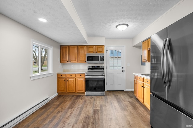 kitchen with stainless steel appliances, a baseboard heating unit, light countertops, and a textured ceiling
