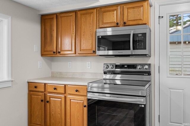 kitchen featuring brown cabinets, light countertops, and appliances with stainless steel finishes